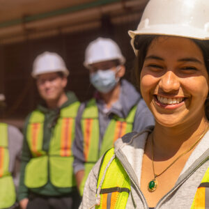 Engineering student stands in front of colleagues enjoying work.